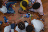 "Group of children sitting on floor sorting and sharing colorful candies during a fun indoor activity."