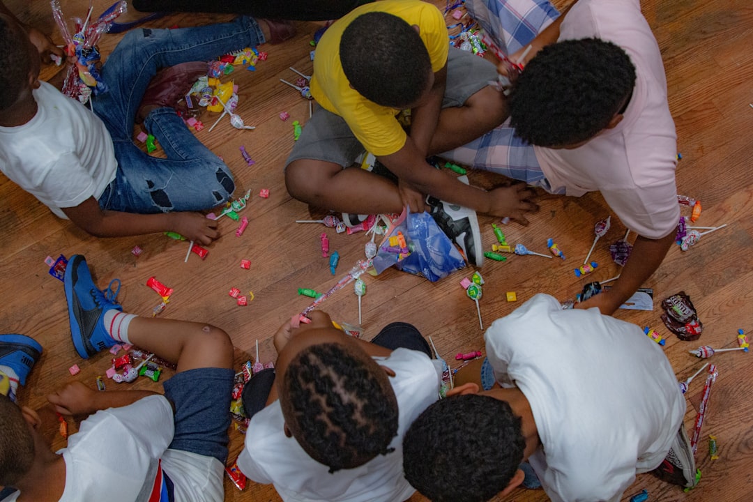 "Group of children sitting on floor sorting and sharing colorful candies during a fun indoor activity."