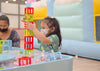 “Little girl playing with colorful building blocks in a play area, developing creativity and motor skills through imaginative play.”